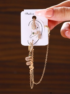 Detail of gold snake earring set with white zircons and green gemstone eyes for ear piercing