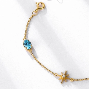 Macro detail of S925 silver gold bracelet with blue topaz and star-shaped pendant charm