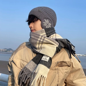 Winter set with grey knit earflap hat and black-white plaid scarf in a coastal setting