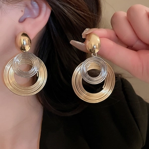 Gros plan de boucles d'oreilles créoles superposées dorées et argentées sur un modèle