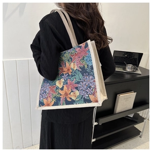 Detail of vintage floral tapestry tote bag with textured patterns and cream woven straps