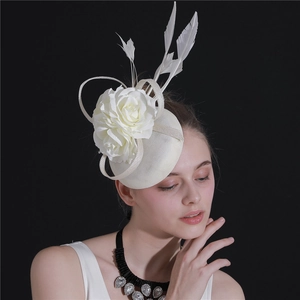 Detail of ivory fascinator hat with mesh flowers and white feathers on a model