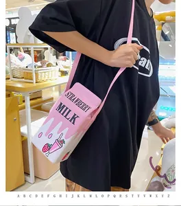 Detail of strawberry milk carton crossbody bag with pink strap worn by a model