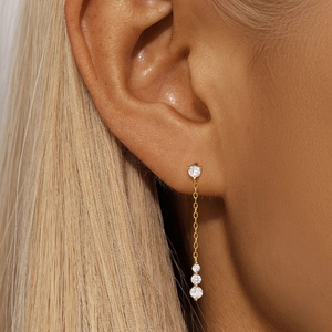 Close-up of gold long-chain s925 silver earrings with sparkling round diamonds on a model