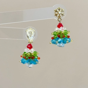 Detailed view of handcrafted beaded Christmas tree earrings with a golden snowflake hook