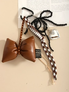 Detail of vintage bow pendant with silver heart charm and houndstooth rope accessory