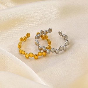 Minimalist gold and silver beaded open rings shown on elegant cream silk fabric background