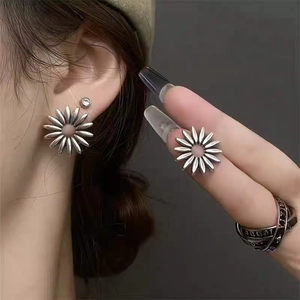 Detail of vintage silver daisy studs and layered ring on model with gray background