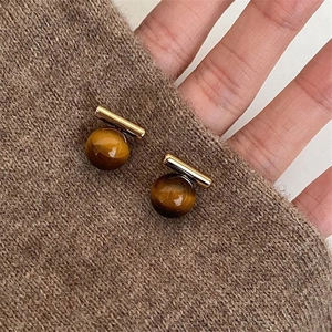 Detail of gold plated hoop earrings with brown tiger eye stone on brown knit sweater
