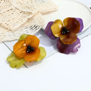 Detailed close-up of handmade acrylic flower brooches with pearly beads and marble texture