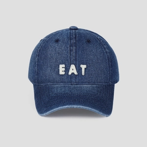 Close-up of white 3D boucle embroidery with EAT letters on navy denim baseball cap