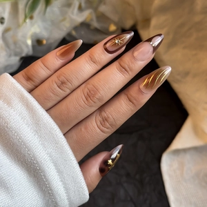 French gradient press-on nails with amber texture, gold accents, and rhinestones on hand