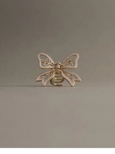 Detail of champagne gold butterfly hair claw clip with intricate hollow patterns and pearls