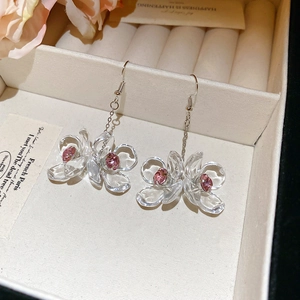 Close-up of transparent acrylic flower earrings with pink crystal and silver hook