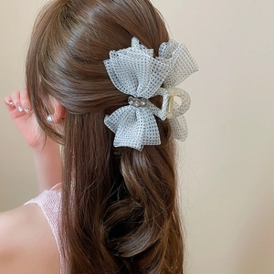 Detailed view of the mesh polka dot bow hair claw clip with rhinestones worn by a model