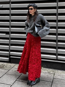 Detailed view of red long skirt with 3D petal texture paired with grey knit sweater