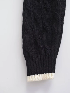 Detail of cable knit texture and contrast ribbed cuffs on a black cardigan