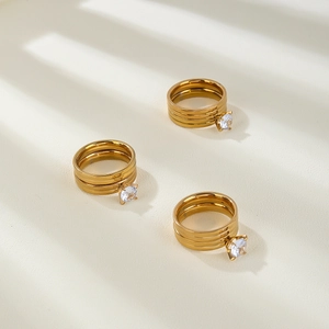 Macro shot of three-layer gold-plated rings with round-cut zircon stones in prong setting