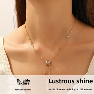 Détail d'un collier papillon doré avec glands en strass sur le cou d'un modèle