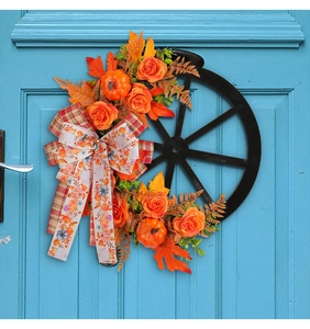 Close-up of autumn pumpkin wheel wreath with orange roses and maple leaves for door decor