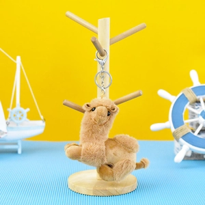 Close-up of a cute brown plush camel keychain pendant hanging on a wooden stand