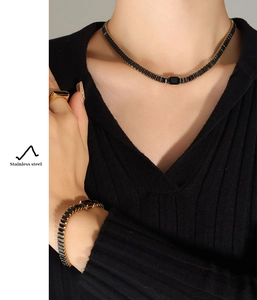 Dettaglio del set di gioielli in acciaio inossidabile dorato con zirconi neri su una modella