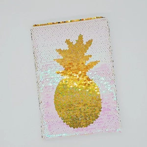 Dettaglio di un taccuino con paillettes reversibili e un motivo a forma di ananas d'oro