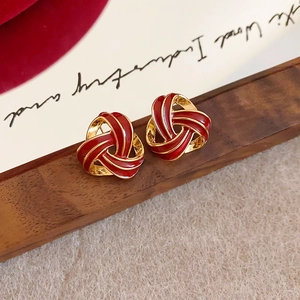 Gros plan détaillé des boucles d'oreilles nœud rétro avec émail rouge et cadre doré