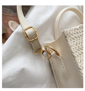 Detail of adjustable strap with gold hardware on a cream daisy woven handbag