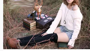 Detail of black cable knit over-knee leg warmers showing thick braided texture and long fit