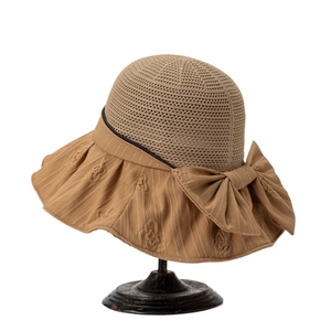 Women's brown hollow sun hat with wide brim and decorative bow on a display stand