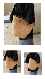 Detail of straw woven tote bag featuring brown leather straps and sturdy metal rivets