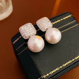 Elegant silver square zircon stud earrings with large round pearls on black jewelry box