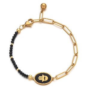 Macro detail of gold paperclip chain bracelet with Hamsa Hand charm and black beads