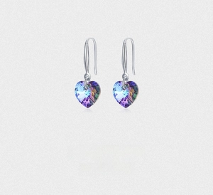 Detail of heart-shaped multifaceted crystal earrings with silver hooks and colorful reflections