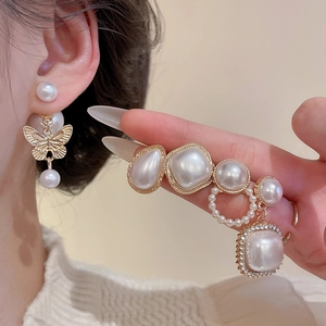 Close-up of gold pearl earring set with butterfly charms and cubic zirconia details