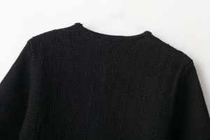 Close-up of black knitted sweater neckline and shoulder texture with fine stitching