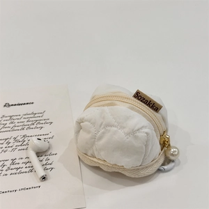 Close-up of cream quilted headphone pouch with zipper and elegant pearl charm detail