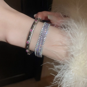 Nahaufnahme von geschichteten Silberarmbändern mit roten Diamanten und lila Tennisarmkette