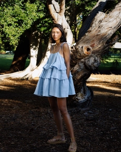 Detail of light blue tiered ruffle mini dress with thin tie straps in a forest setting