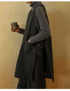 Detail of dark green cotton linen apron with large pocket and side ties on a model