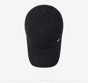 Top view of a black baseball cap with a golden triangle metal logo on a clean gray base