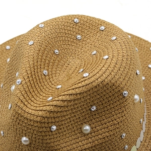 Detailed texture of straw sun hat with elegant pearl and rhinestone embellishments
