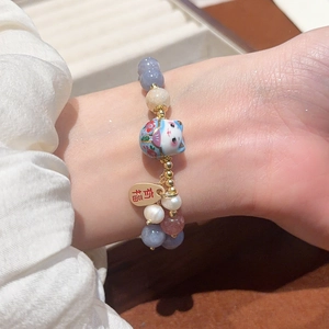 Dettaglio del bracciale di cristallo con gatto portafortuna e ciondolo Youfu dorato