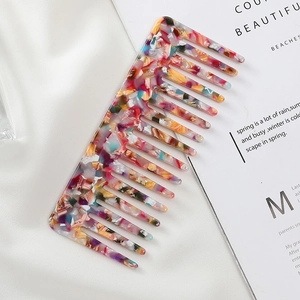 Detailed view of acetate wide tooth comb with marble pattern on white silk background