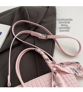Detail of pink woven bucket bag featuring adjustable strap and floral silk scarf handle