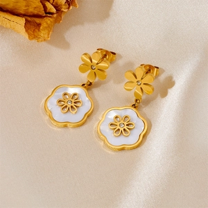 Elegant gold-plated shell flower earrings with small rhinestones on beige silk background