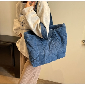 Détails de la texture denim matelassée et des coutures sur ce grand sac fourre-tout bleu