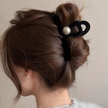 Macro detail of elegant black velvet hair claw clip with large white pearl on model