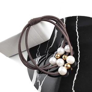 Détail de l'élastique à cheveux marron café à trois fils avec perles blanches et billes dorées